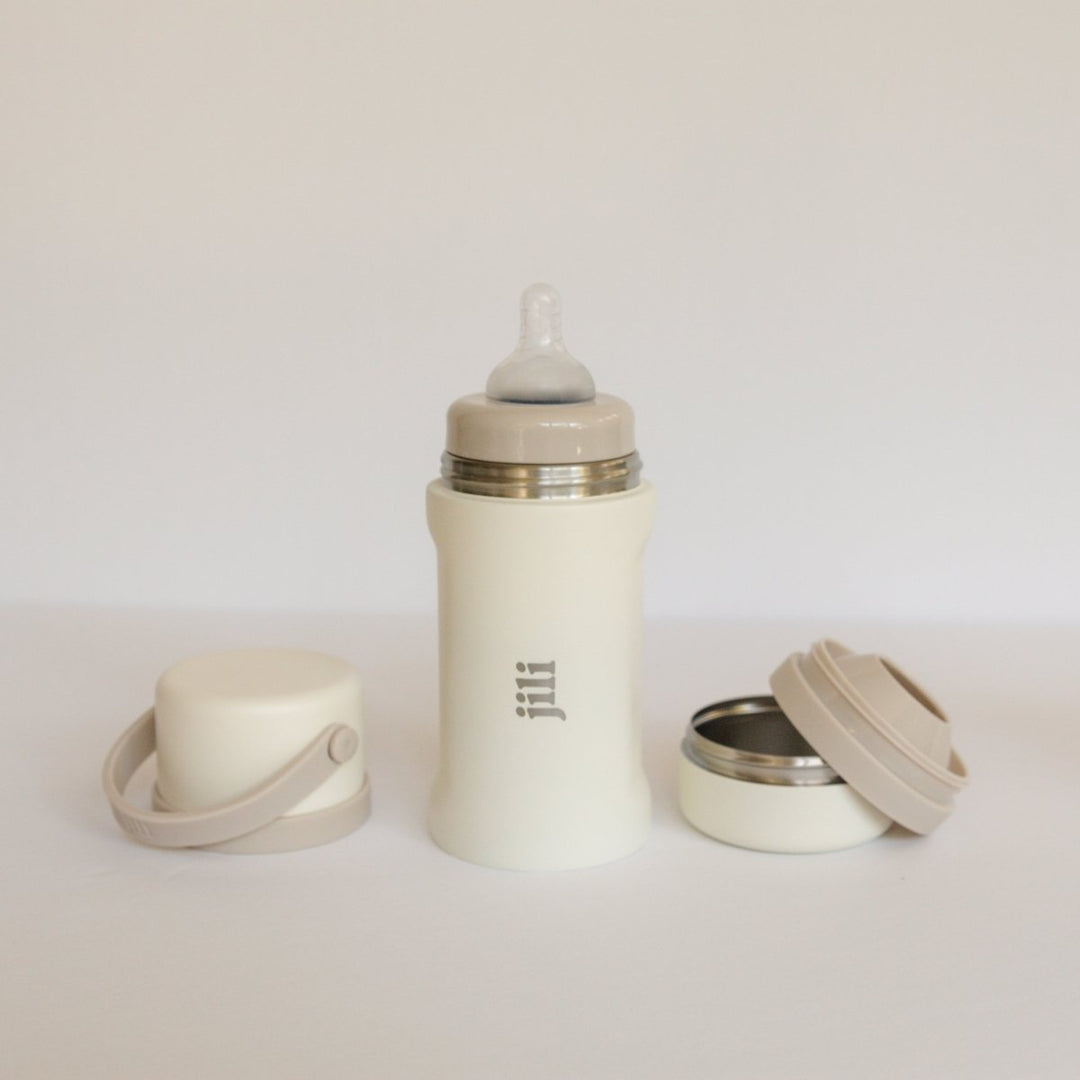 Beige baby bottle with accessories on a light gray background