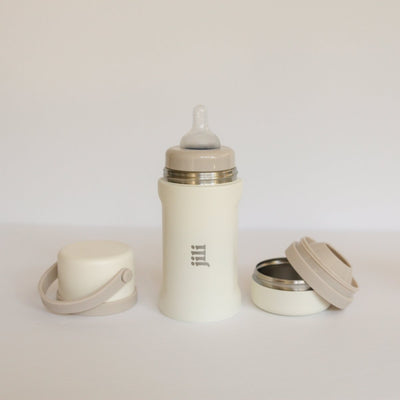 Beige baby bottle with accessories on a light gray background