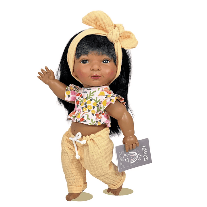 Doll with long black hair, floral top, and yellow pants on a white background