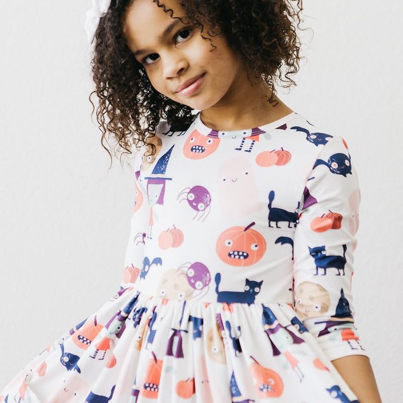 Child wearing a colorful patterned dress with a plain background