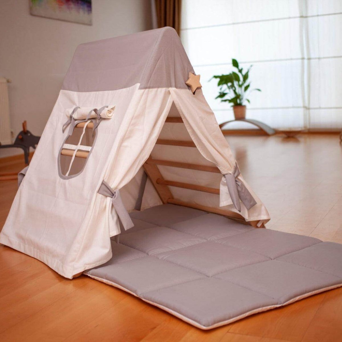 Children's play tent with a cushioned floor on a wooden floor.