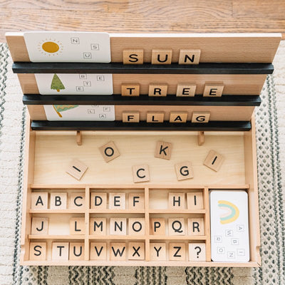 Wooden toy with letter blocks and alphabet chart on a wooden surface