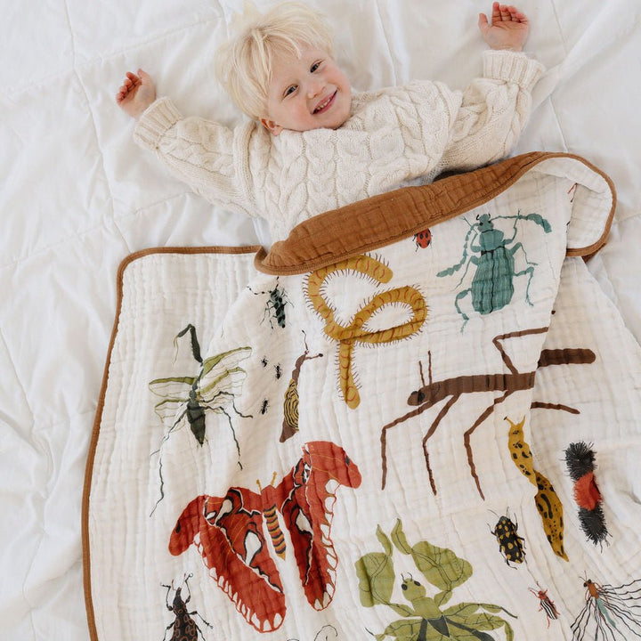 Child lying on a blanket with insect illustrations on a white background