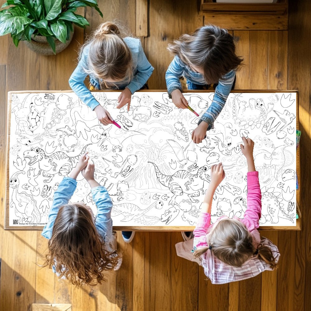 Four children coloring on a large sheet of paper with animal designs on a wooden floor.