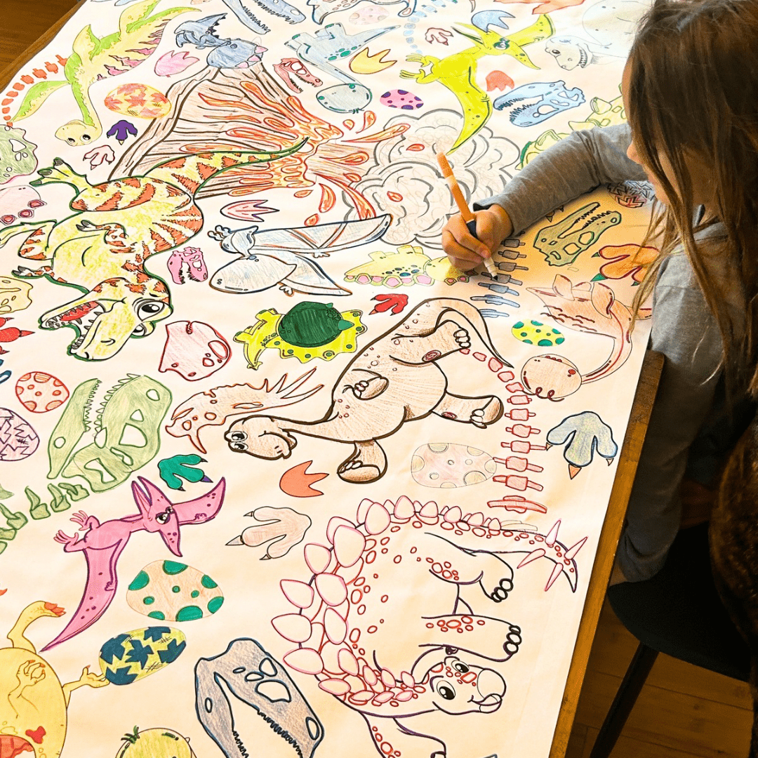 A kid is coloring a large sheet of dinosaur illustrations with crayons.