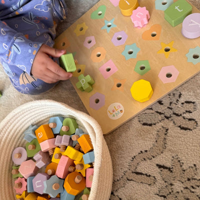 Child playing with colorful wooden letters on a mat and in a basket.