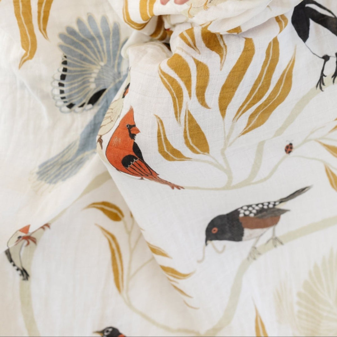 Baby wrapped in a blanket with bird patterns on a white background