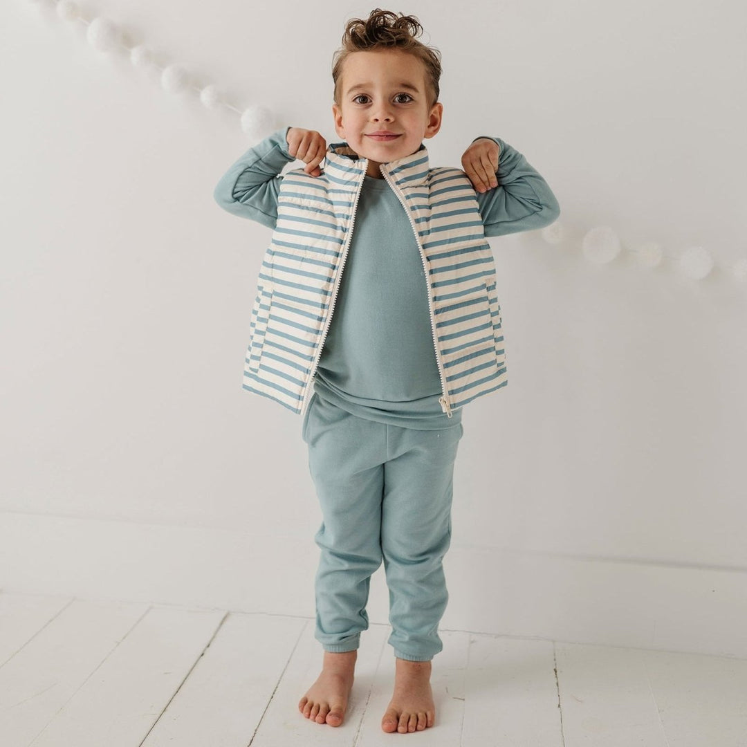 Child wearing a striped shirt and light blue pants against a white background