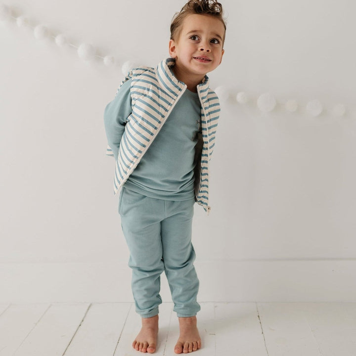 Child wearing a light blue outfit with a striped jacket on a white background