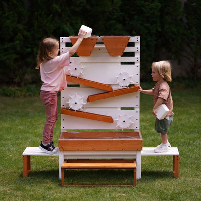 Two children playing with a wooden climbing structure in a garden.
