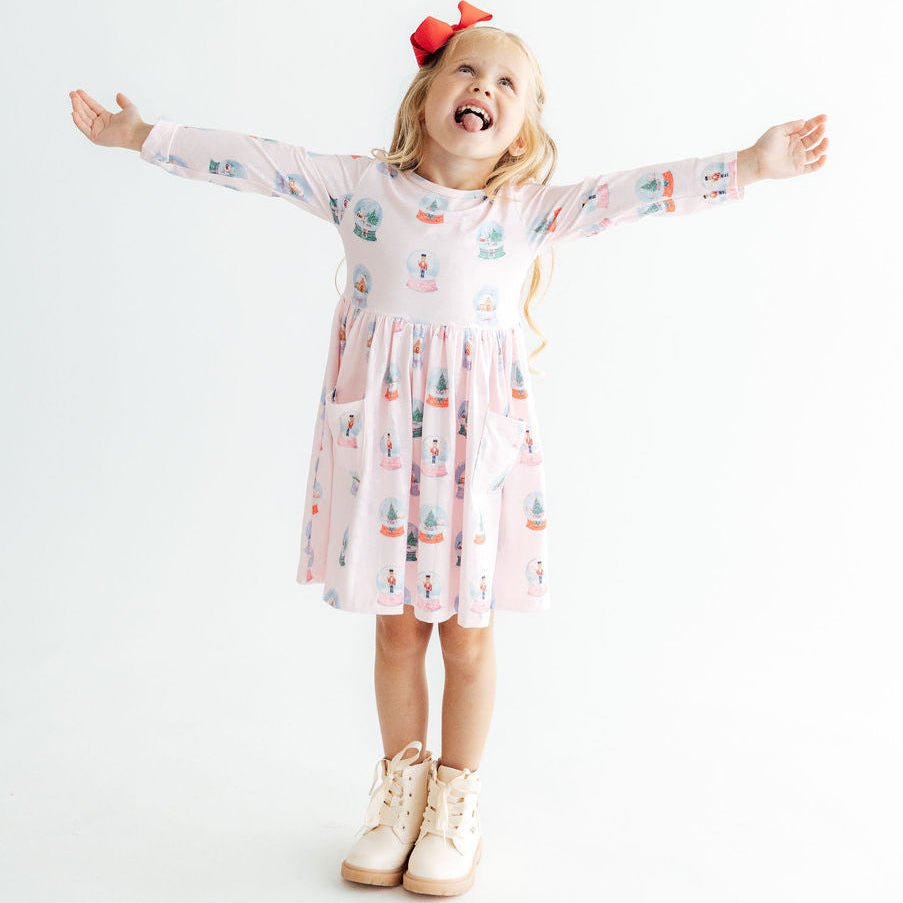 Young girl in a patterned dress with arms outstretched on a white background