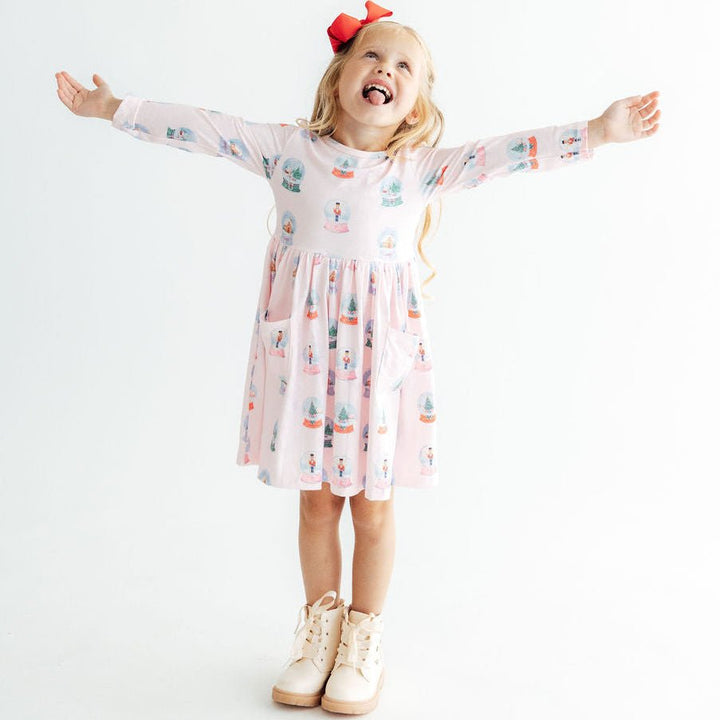 Young girl in a patterned dress with arms outstretched on a white background