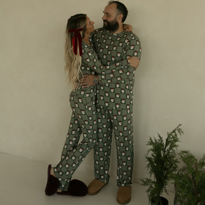 Two people in matching green pajama sets standing close together against a plain background.