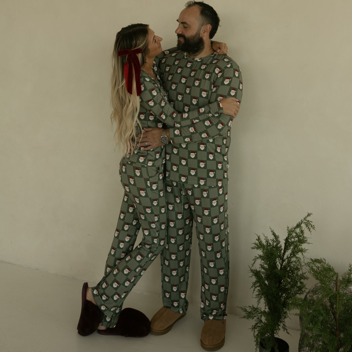 Two people in matching green pajama sets standing close together against a plain background.
