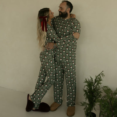 Two people in matching green pajama sets standing close together against a plain background.
