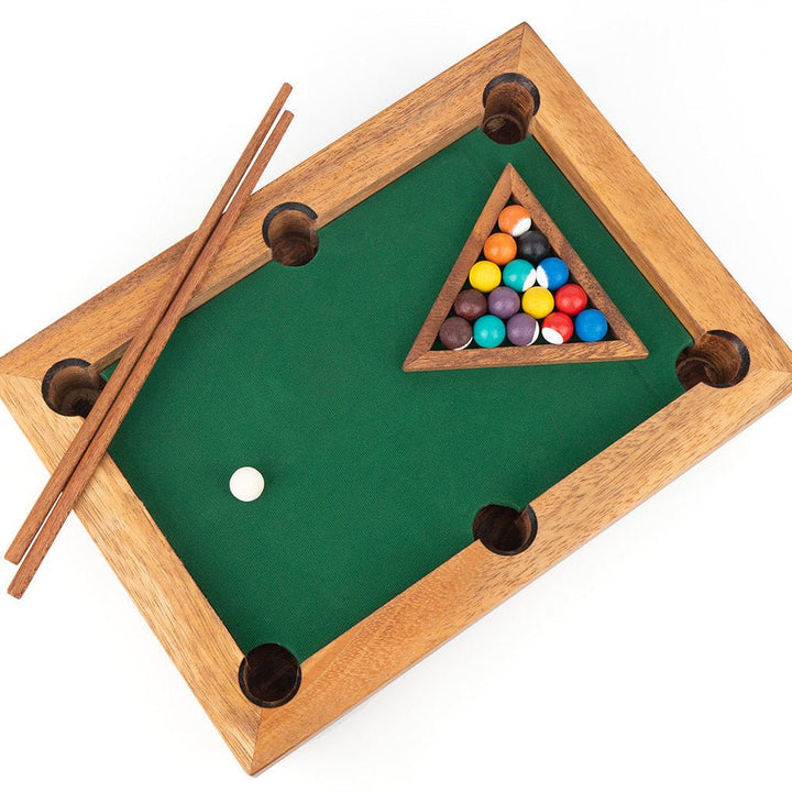 Miniature pool table with balls and cues on a white background