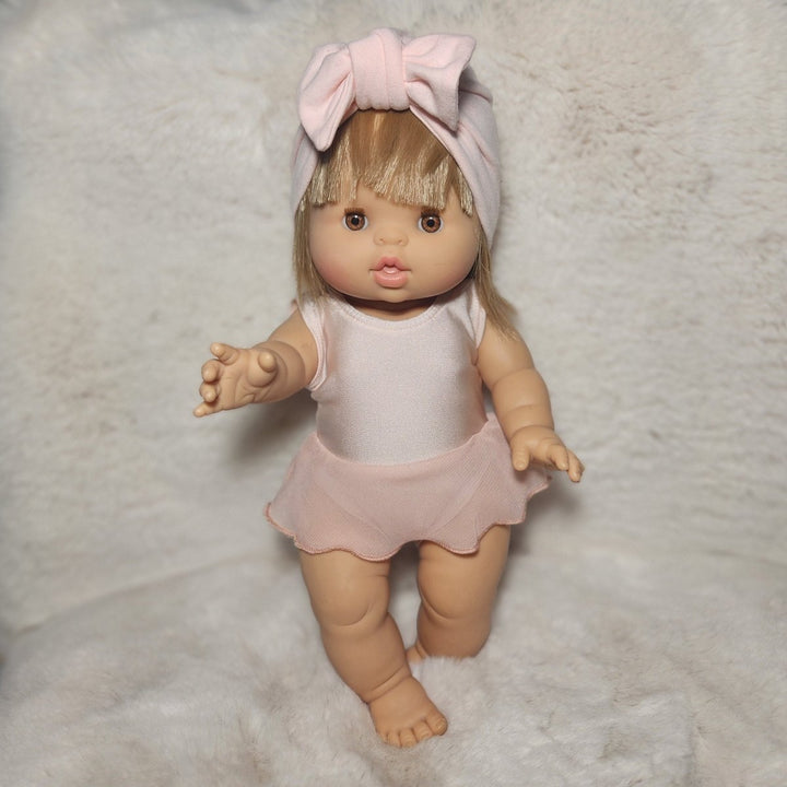 Doll with blonde hair and pink outfit lying on a textured surface