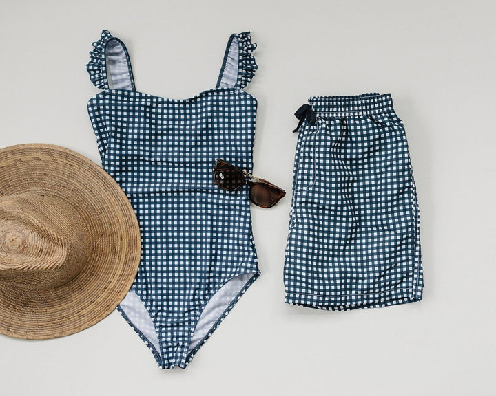 Blue and white checkered swimsuit with matching shorts and a straw hat on a light background