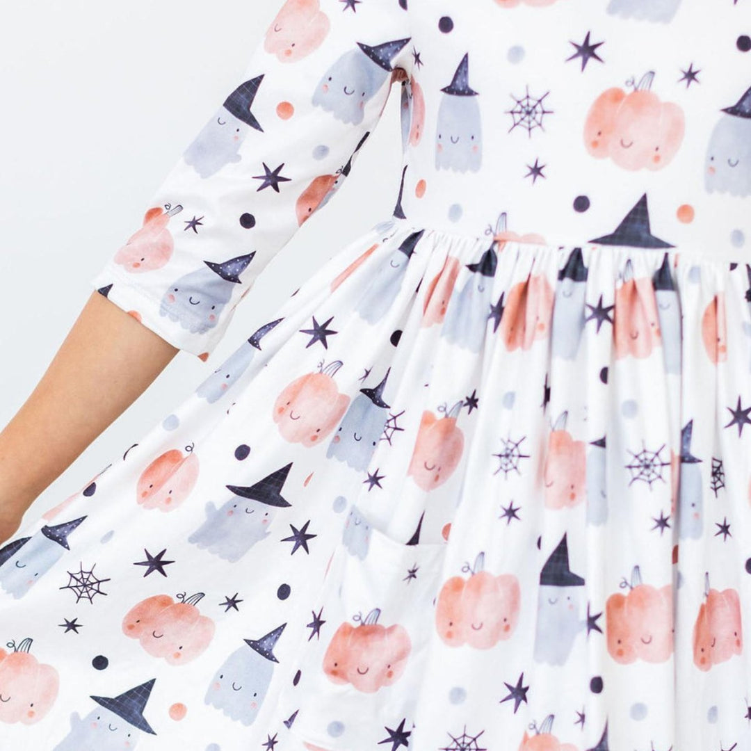 Dress with Halloween-themed pattern featuring pumpkins, ghosts, and witches on a white background.