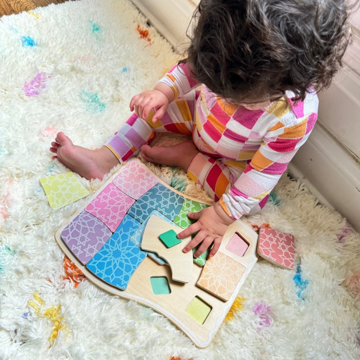 Child playing with a colorful wooden puzzle on a fluffy rug.