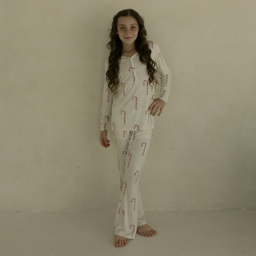 Person wearing a pajama set with candy cane pattern against a beige background