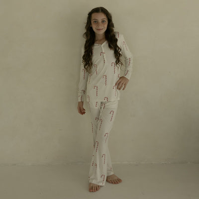 Person wearing a pajama set with candy cane pattern against a beige background