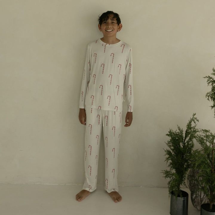Person wearing a pajama set with candy cane pattern in a minimal indoor setting