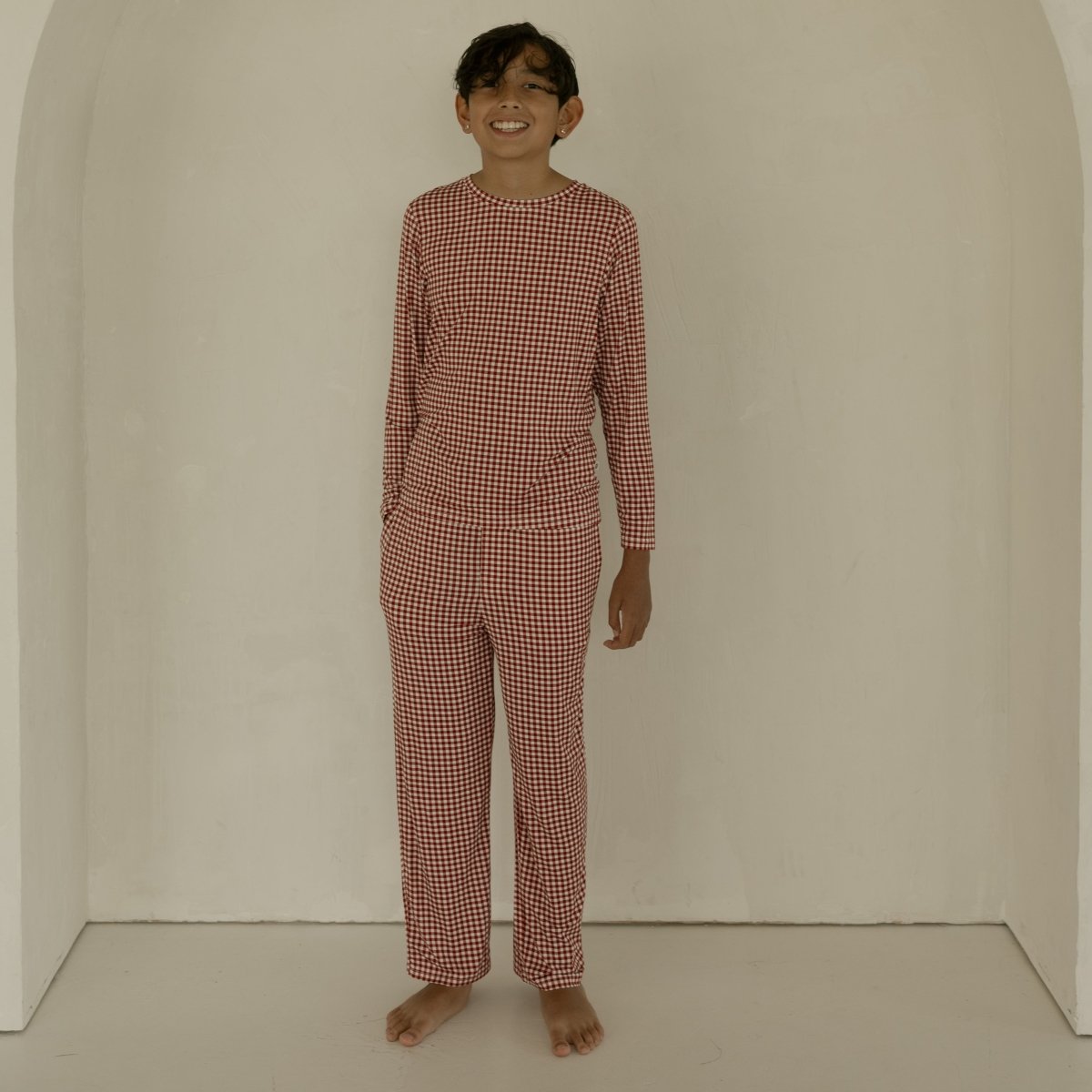 Person wearing a red checkered outfit standing in front of an archway.