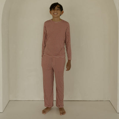 Person wearing a red checkered outfit standing in front of an archway.