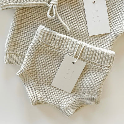 Knitted baby outfit with a top and shorts on a white background