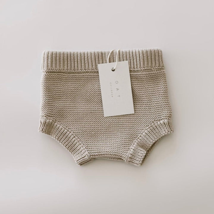 Knitted baby bloomers with a tag on a light background