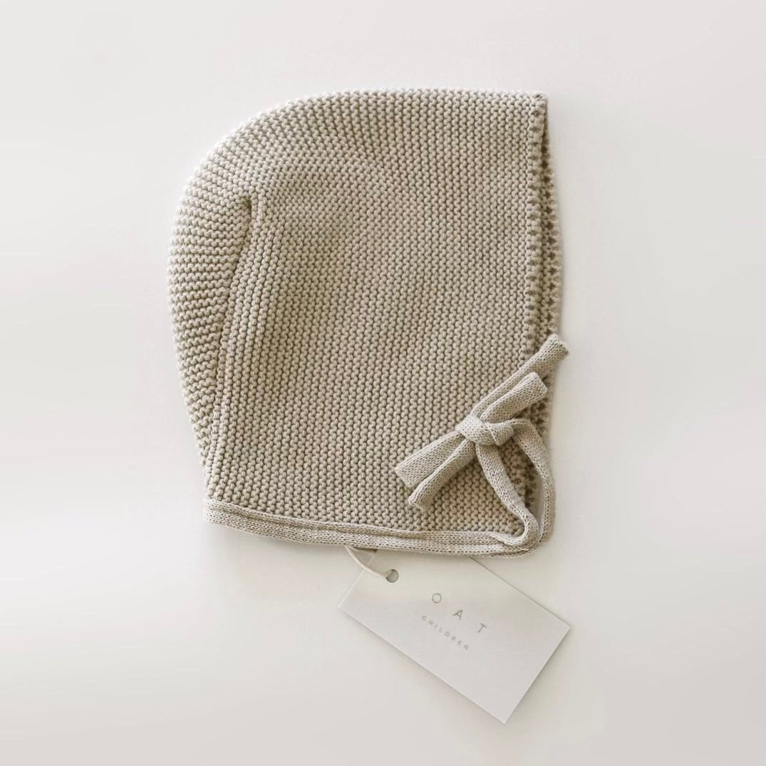 Knitted baby bonnet with a bow on a white background