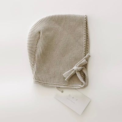 Knitted baby bonnet with a bow on a white background