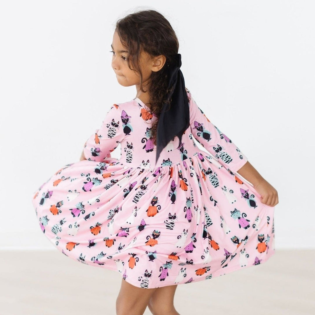 Young girl twirling in a pink floral dress on a white background