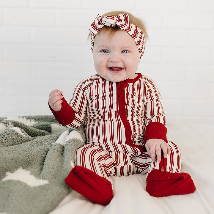 Baby in red and white striped outfit with matching headband on a white background
