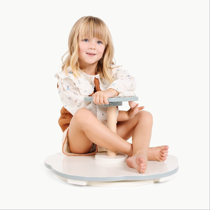 Child sitting on a white balance board with a plain background