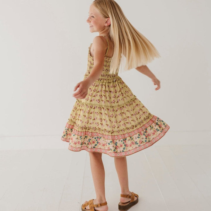 Young girl in a floral dress twirling on a white floor.