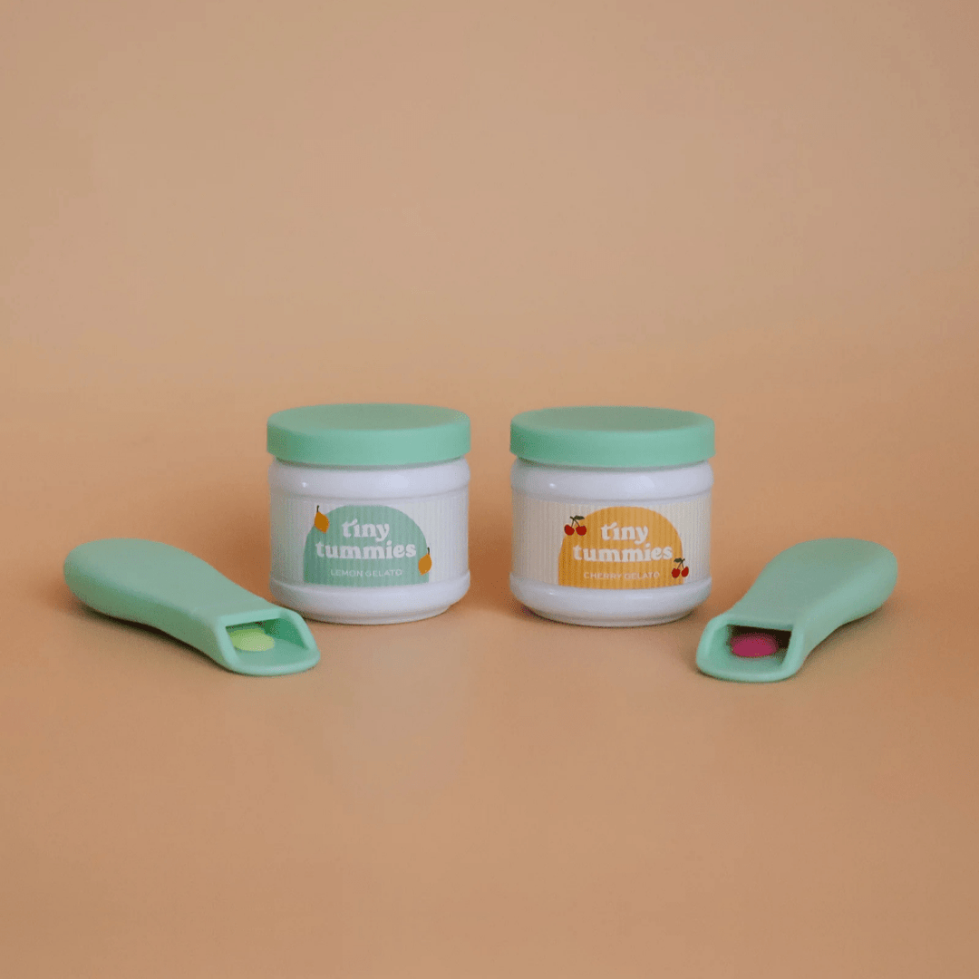 Two containers with green lids and matching spoons on a beige background