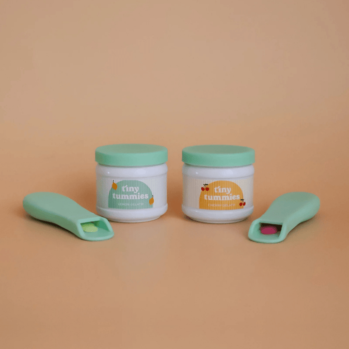 Two containers with green lids and matching spoons on a beige background