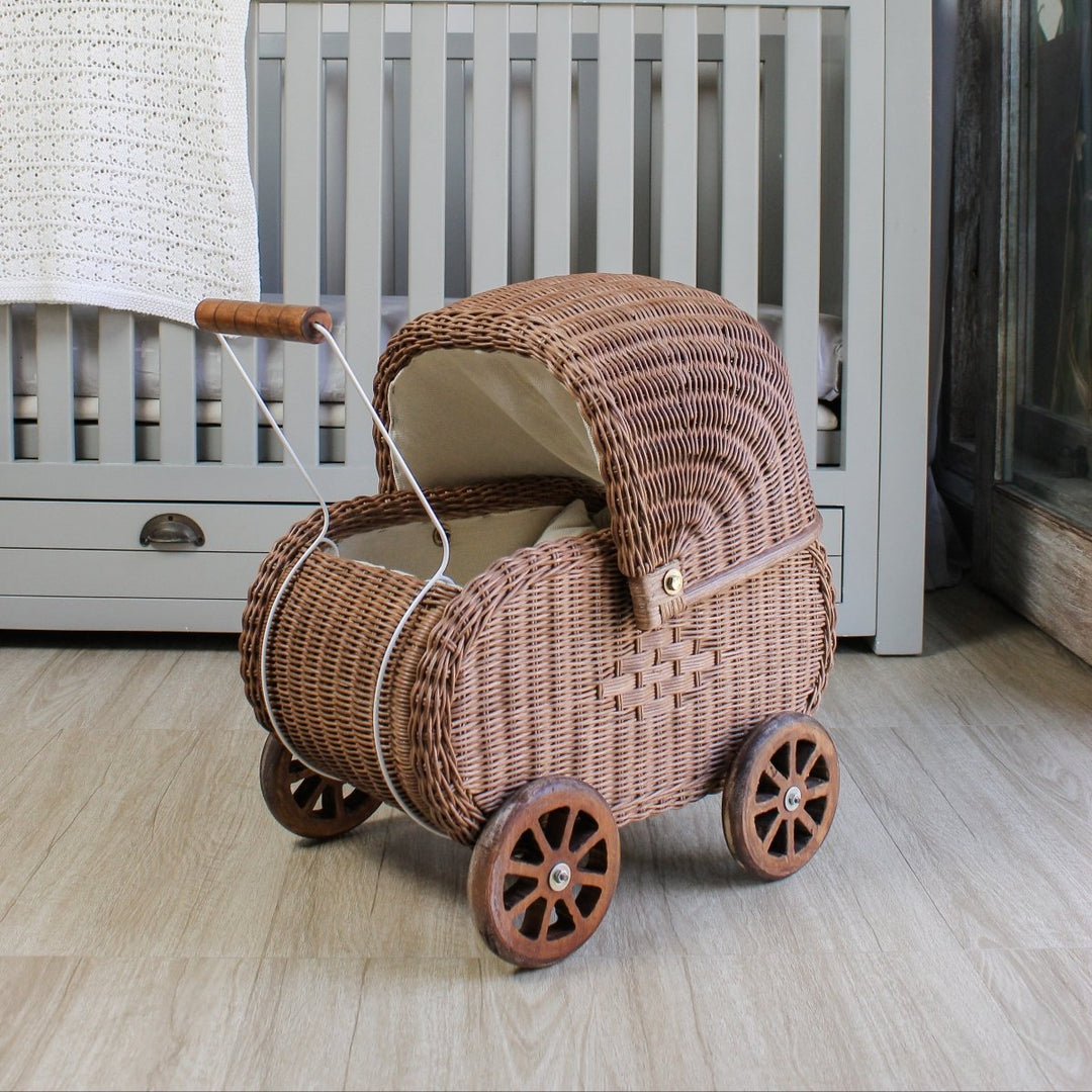 Wicker baby buggy in a nursery with a crib and decorative wall art.
