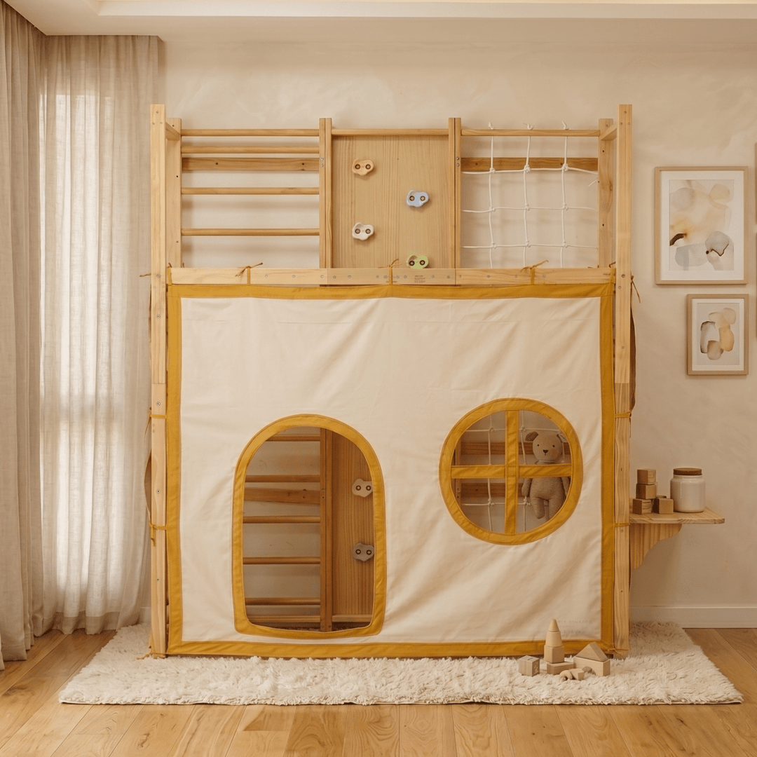 A wooden loft playhouse with an attached cream fabric play tent, featuring arched and oval window openings with yellow trim, a climbing ladder, and a rope net on the upper loft, shown in a styled children&