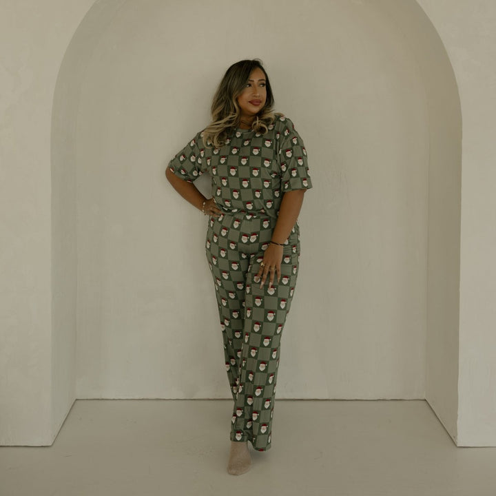 Woman in a green patterned outfit standing in a white archway.