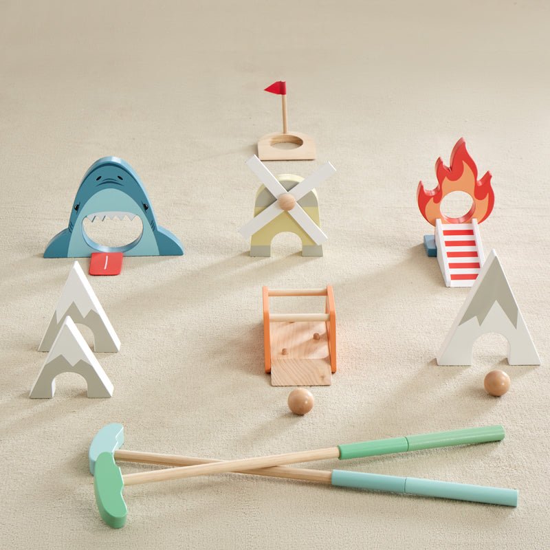 Set of wooden mini golf including a shark, house, and campfire on a beige surface.