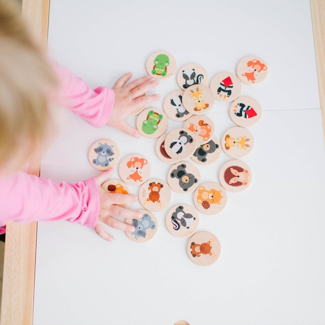 Child playing with animal-themed wooden stamps on a white paper
